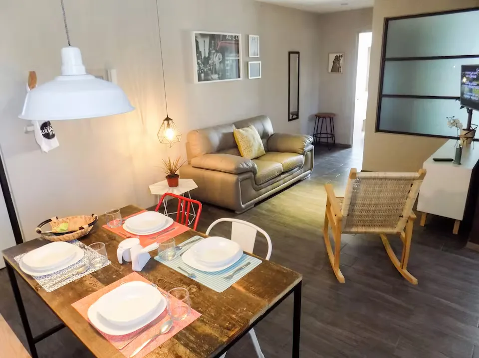Comedor y sala del apartamento boutique Suites 509, Pachuca: mesa para cuatro, sofá de piel y decoración contemporánea