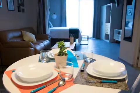 Comedor de Suite Ejecutiva Suites 509, Pachuca: mesa lista para dos, cubiertos turquesa y planta decorativa en loft amueblado