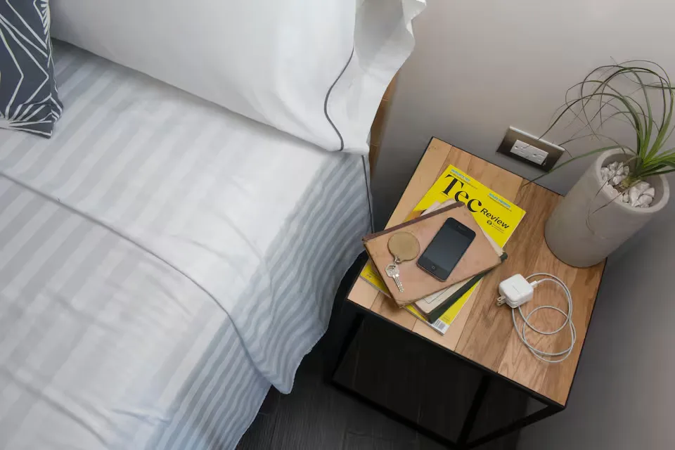 Recámara de Suite Ejecutiva Suites 509, Pachuca: cama con sábanas a rayas, mesita de noche de madera y detalles para huéspedes