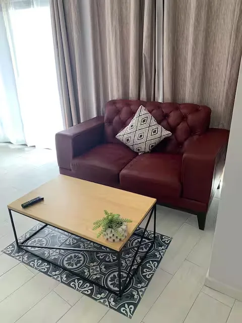Sala de estar en Suite Terraza Suites 509, Pachuca: sofá de piel color vino, mesa de centro de madera y luz natural