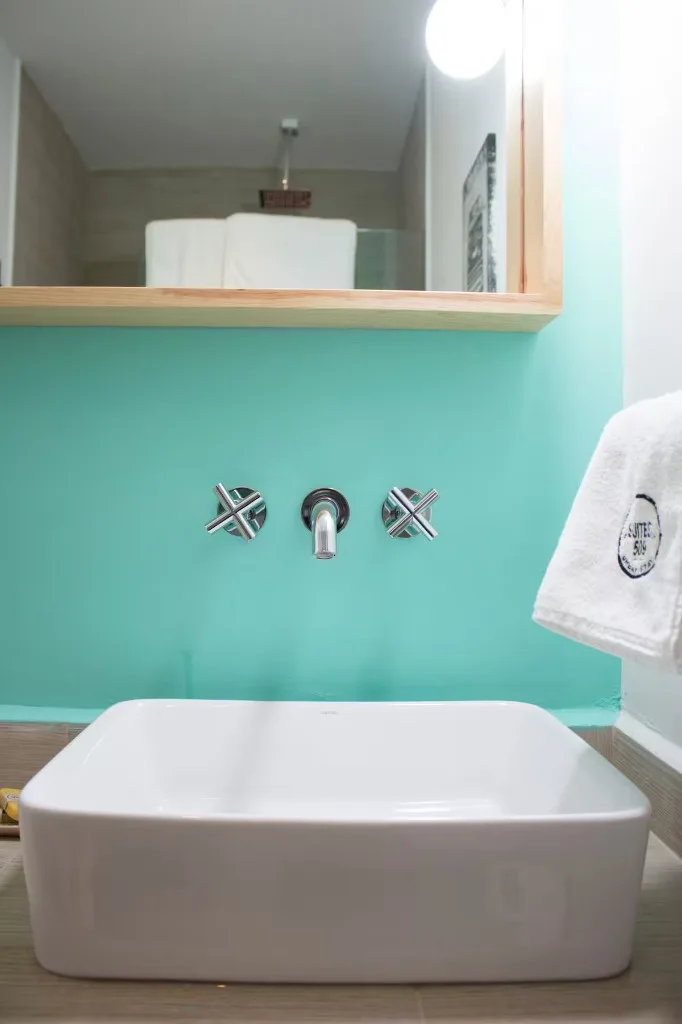 Baño de Suite Ejecutiva en Suites 509, Pachuca: lavabo sobre encimera, pared turquesa, grifería cromada y toallas Suites 509