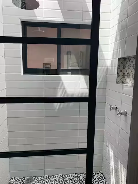 Baño con regadera tipo lluvia en Suite Terraza Suites 509, Pachuca: azulejo blanco, piso geométrico y acabados cromados