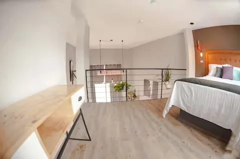 Tapanco del Loft de diseño en Suites 509, Pachuca: recámara luminosa con piso de madera y vista al nivel inferior