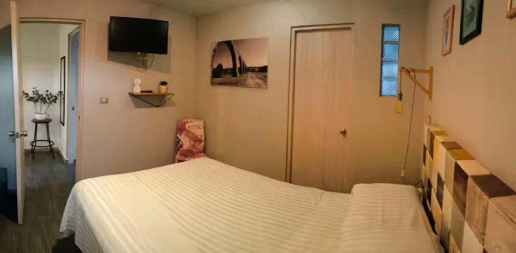 Segunda recámara del apartamento boutique Suites 509, Pachuca: TV en pared, cabecera de colores y vista al pasillo