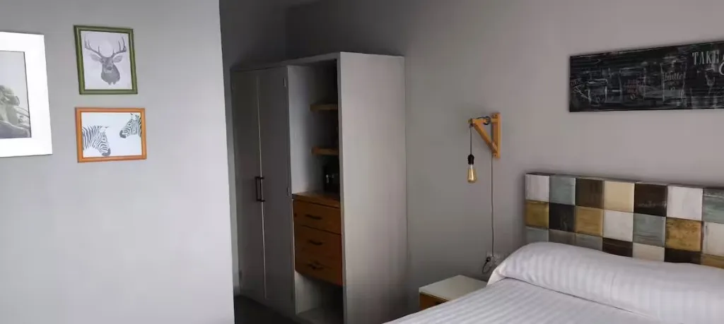 Recámara con clóset en Suites 509, Pachuca: cabecera artesanal de madera, lámpara industrial y almacenamiento amplio