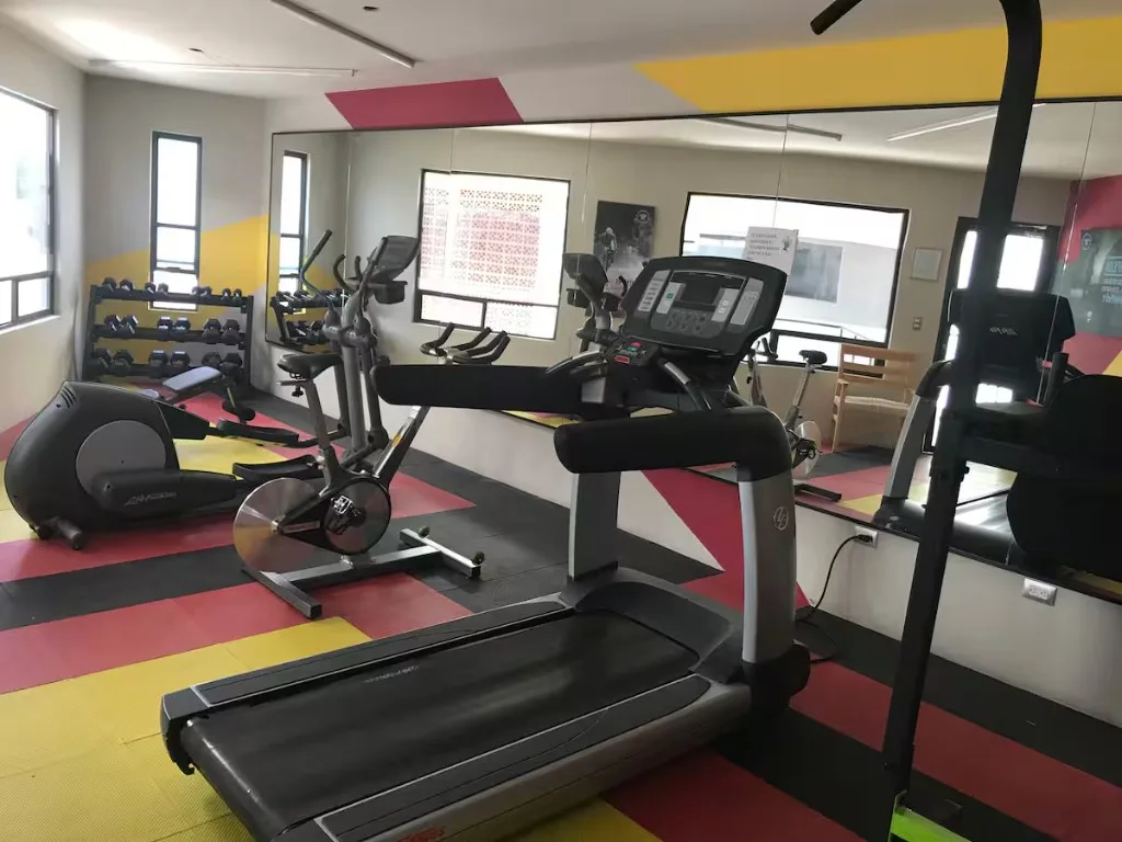 Gimnasio compartido de Suites 509 en Pachuca: caminadora Life Fitness, elíptica, bicicletas y pesas — abierto 24 horas