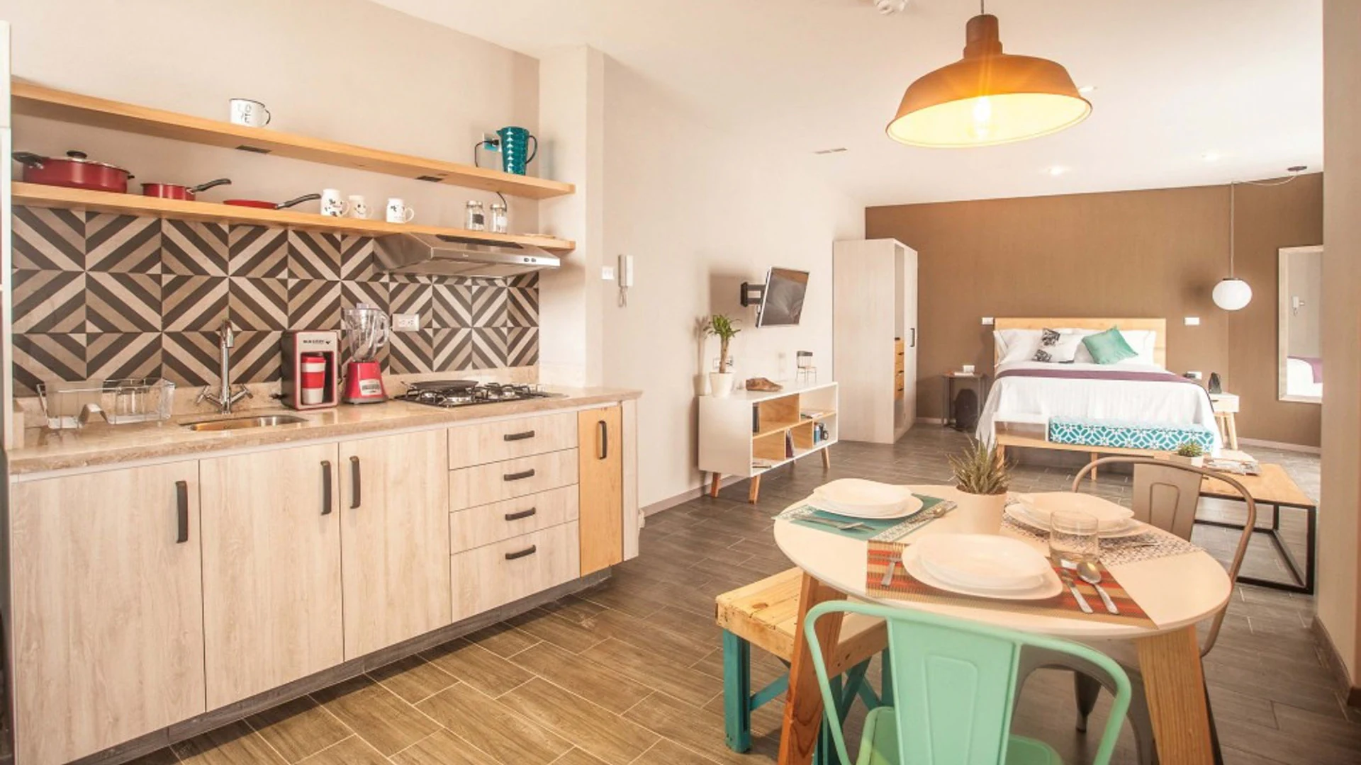Estudio en Suites 509, Pachuca: cocina equipada, mesa de comedor, lámpara colgante y recámara con pared chocolate