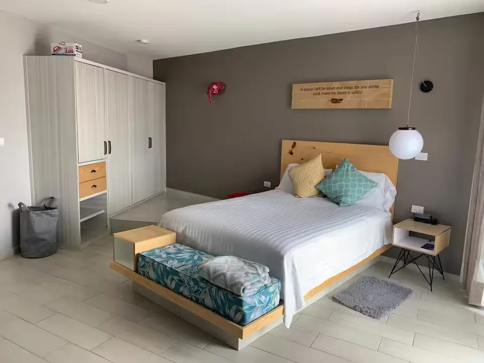 Recámara de Suite Terraza Suites 509: cama con cabecera de madera, clóset amplio y decoración cálida en Pachuca